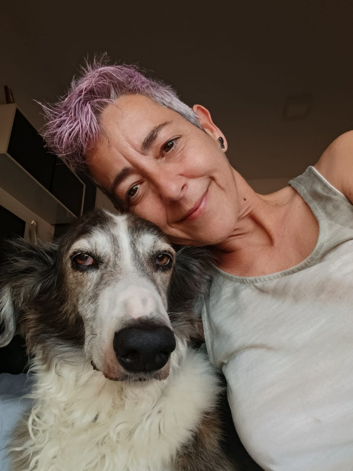 Ángela, con camiseta gris, apoyada junto a Ron en casa